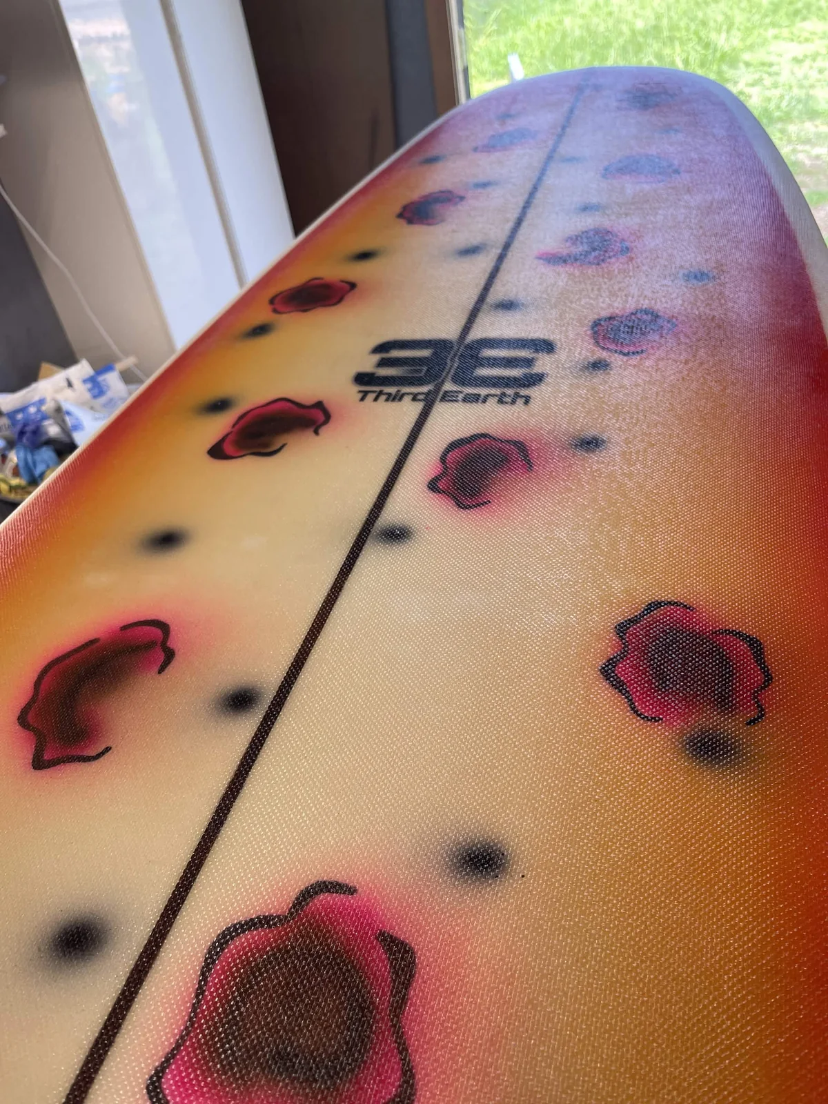 Close view of the Third Earth logo beneath fiberglass on an orange board