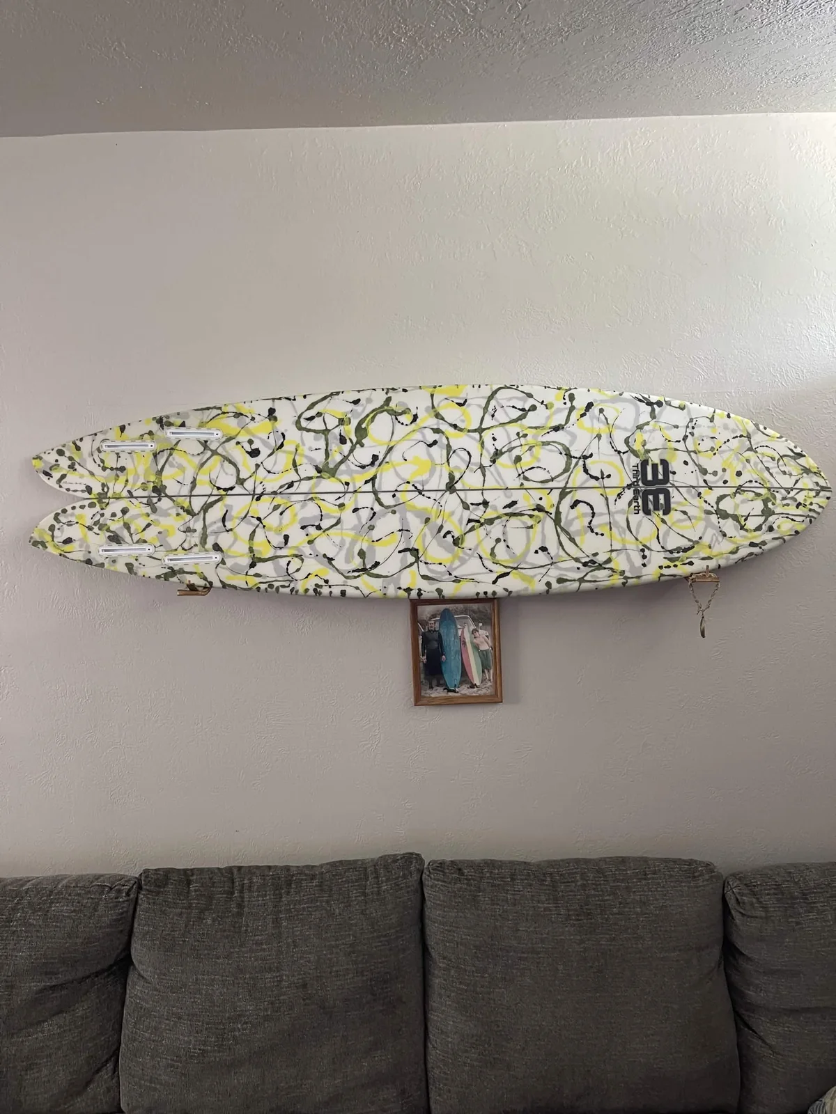 Finished splatter-pattern Third Earth fish surfboard displayed on a wall