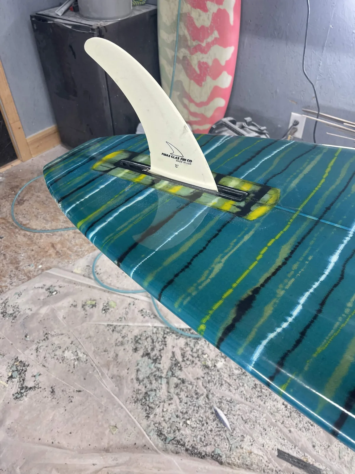 Single fin installed on a teal striped custom surfboard