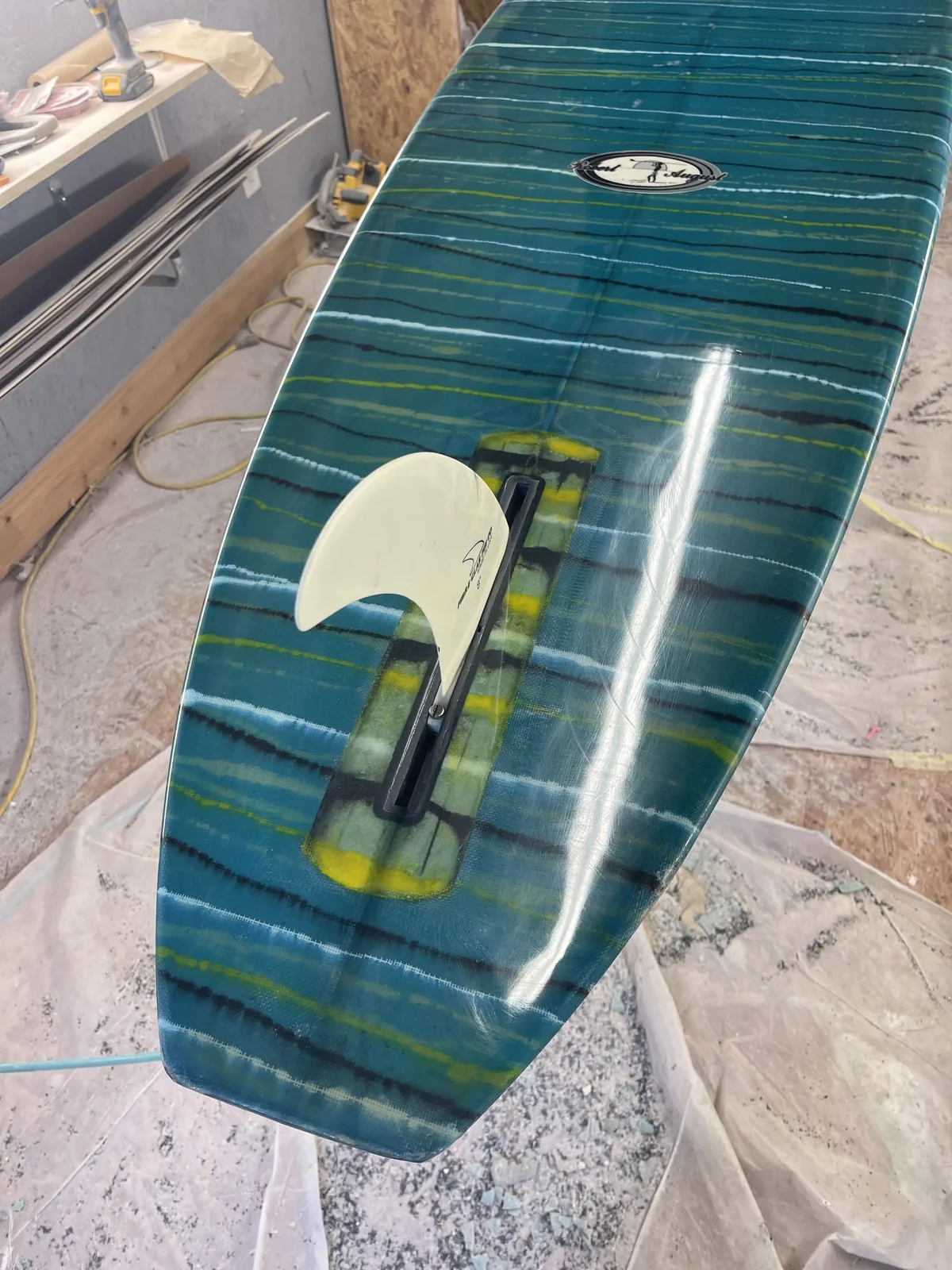 Glossy teal striped surfboard tail and fin box