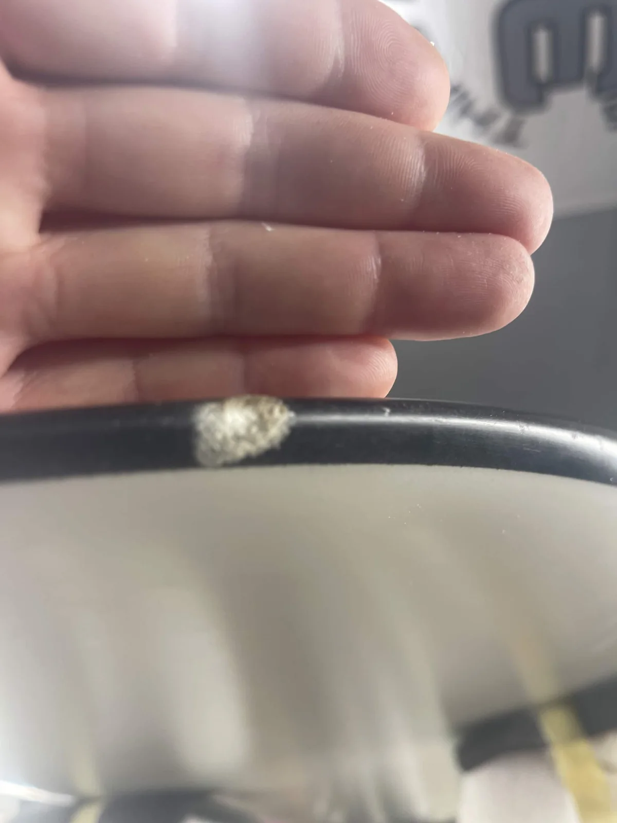 Small damaged spot on the black rail of a white surfboard