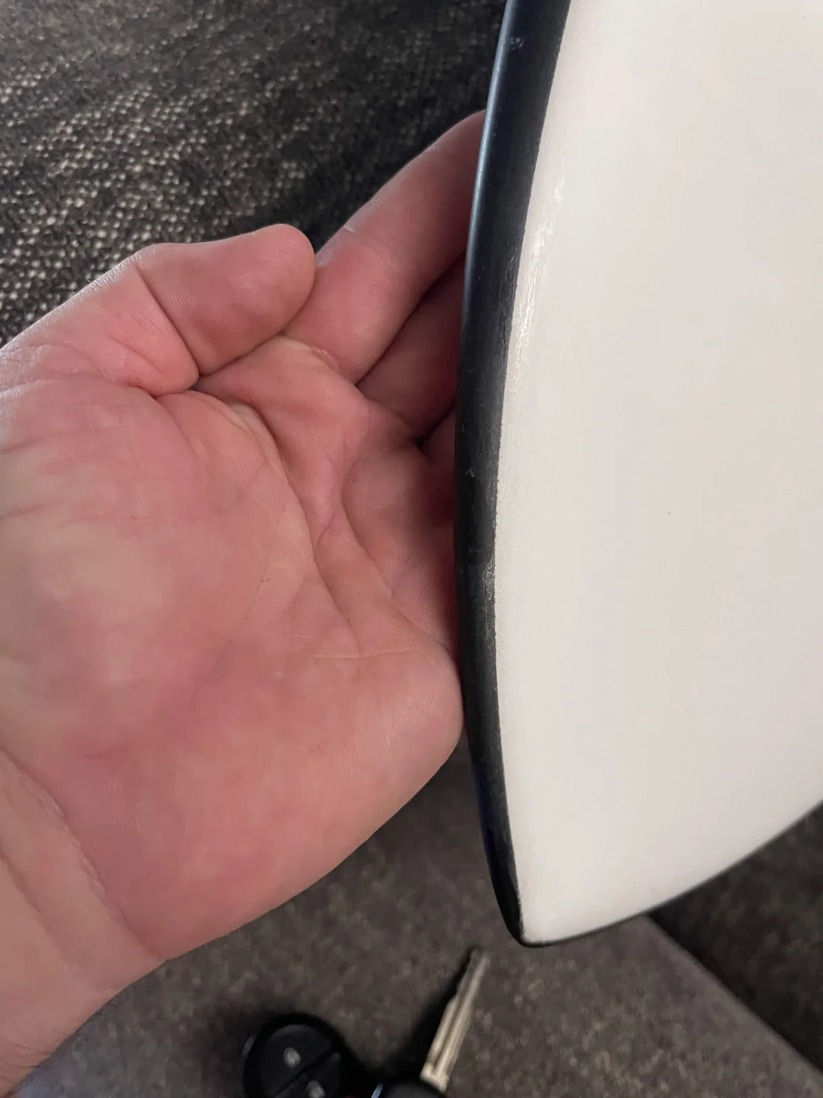 Finished smooth black rail on a white surfboard