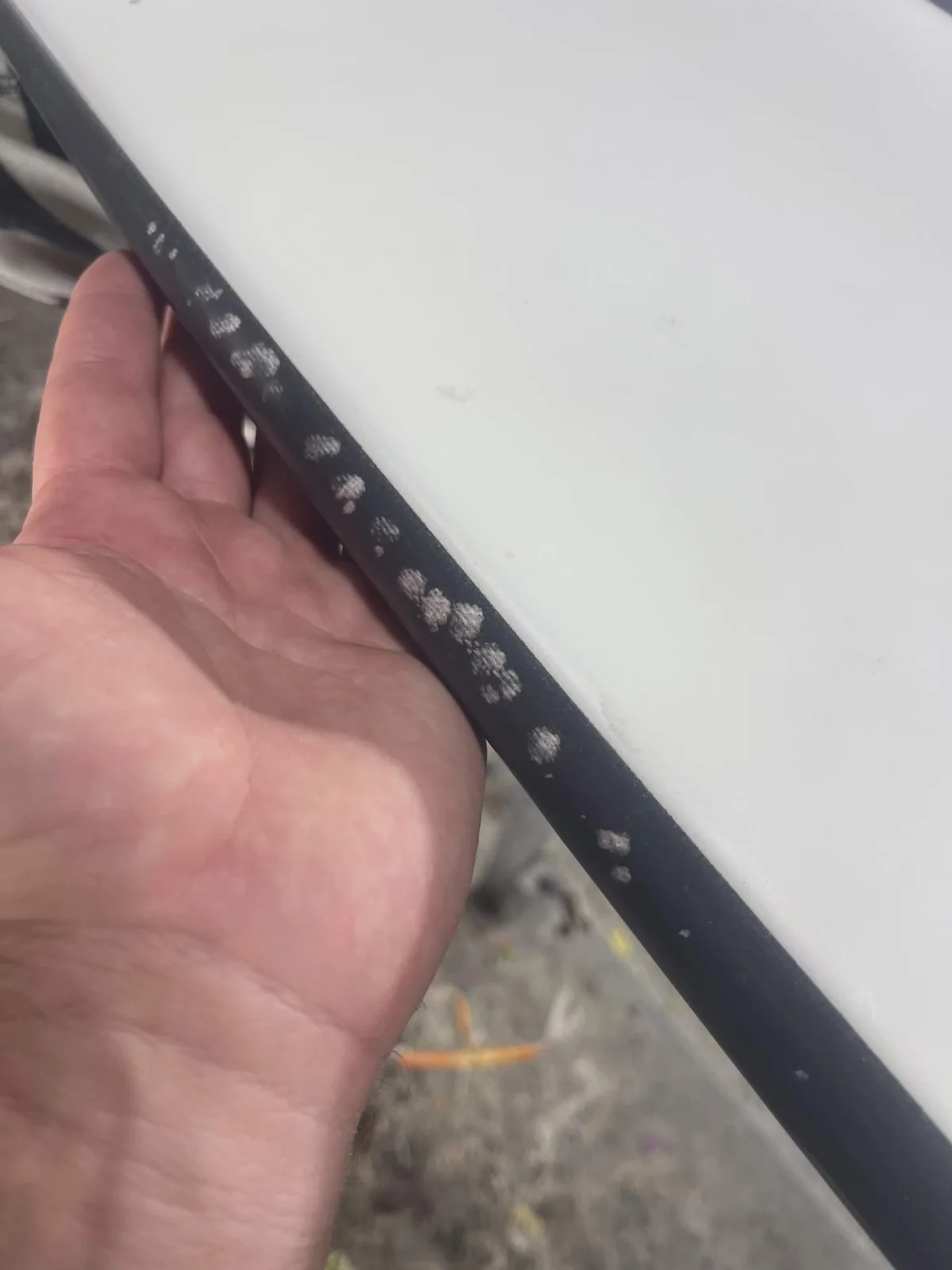 Multiple prepared repair spots along a black surfboard rail