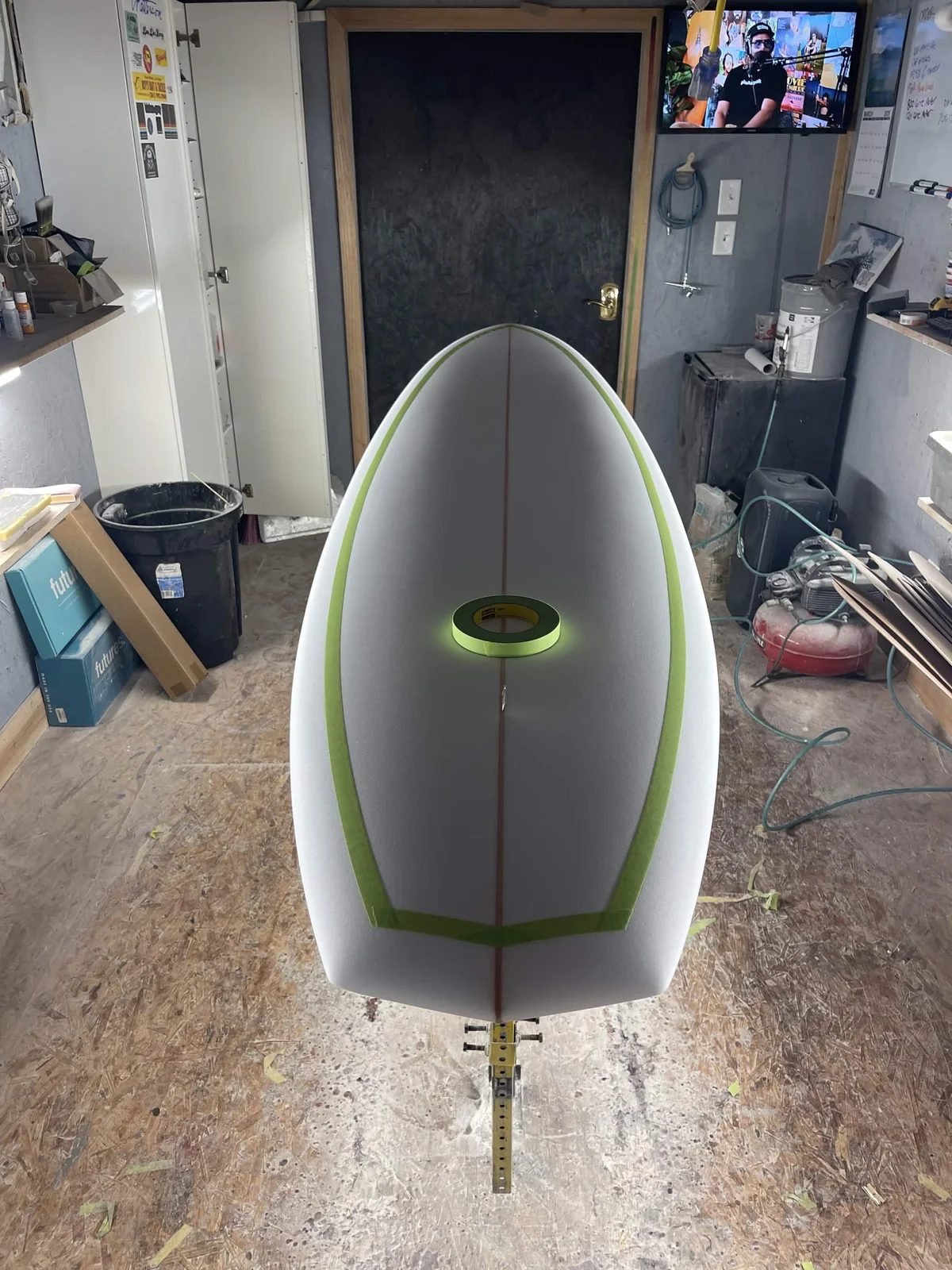 Green tape defining the deck transition on a foam surfboard